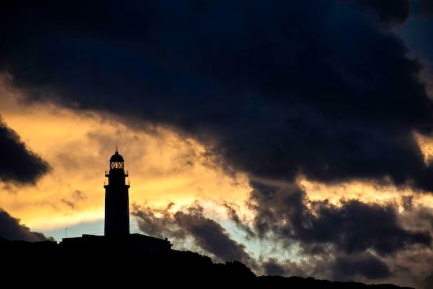 Bewölkter Himmel mit einem Leuchtfeuer in der Silhouette