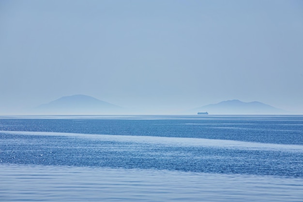 Bewölkter Horizont und Nebel über dem natürlichen Hintergrund der Meereswellen Frachtschiff am Horizont