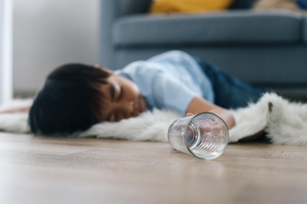 Bewusstloses kleines Kind liegt auf dem Boden mit gefallenem Glas Unfall oder Ohnmachtsbegriff