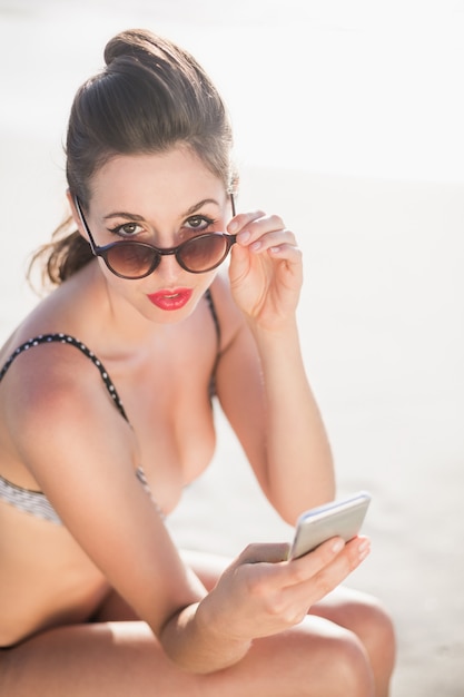 Bezaubernde Frau im Bikini, der über Sonnenbrille schaut
