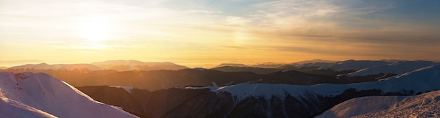 Bezaubernde schöne Aussicht auf die Berge und Hügel im verschneiten Tal am späten Abend