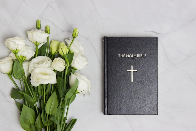 Bibel mit weißen Rosen auf Marmor-Hintergrund mit Notizbuch