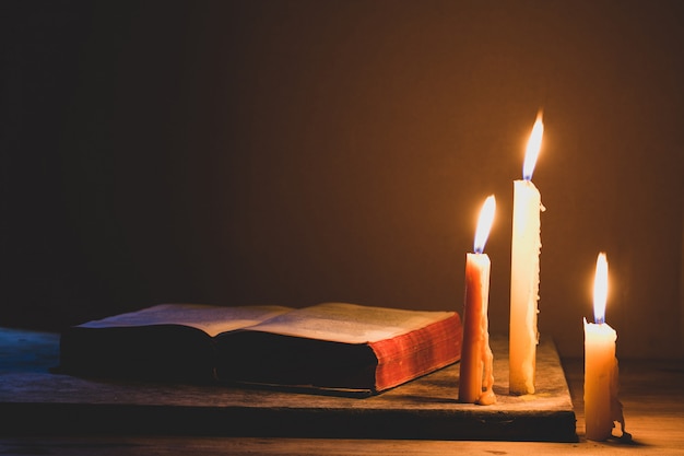 Bibel und Kerze auf einem alten Eichenholztisch. Schöner goldener Hintergrund. Religion-Konzept