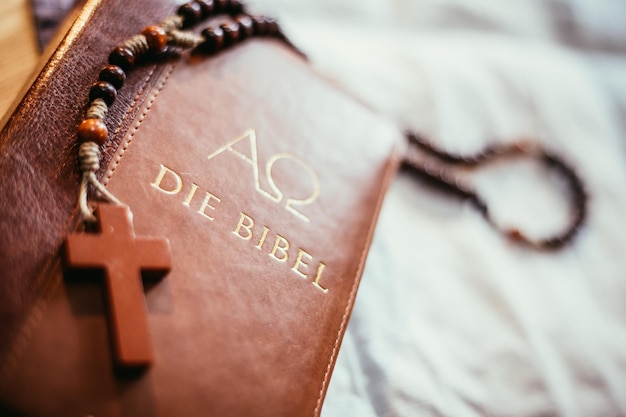 Bibel und Rosenkranz Christliche Bibel und Rosenkranz auf einem Holztisch
