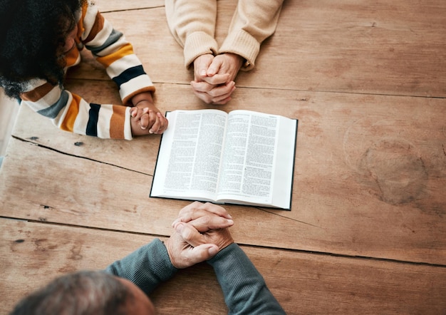 Bibellesebuch oder Hände der Oma mit Kindern zur Unterstützung des Gottesdienstes oder zur Hoffnung auf Bildung im Christentum. Kindergeschwister oder Großmutter lernen gemeinsam das Beten oder lernen Gott in der Religion