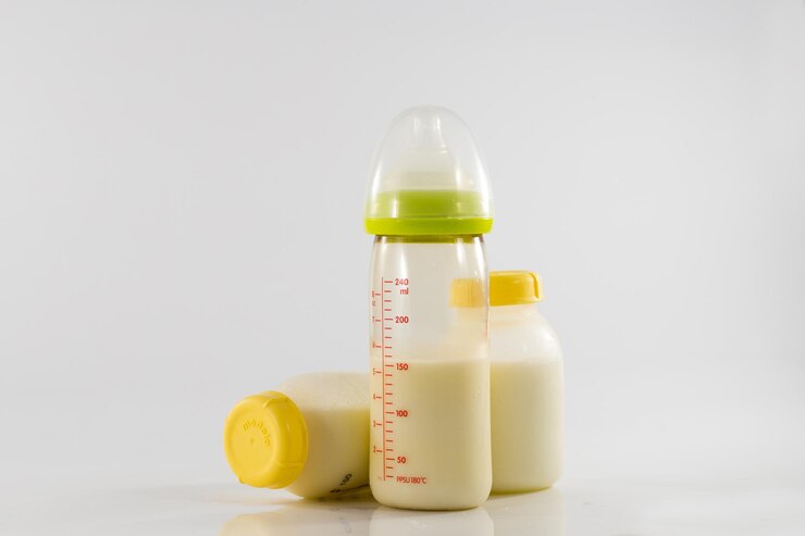 Biberón con leche y una escala de medición en el fondo de un montón de botellas llenas de leche materna. Leche materna: el alimento más saludable para el recién nacido