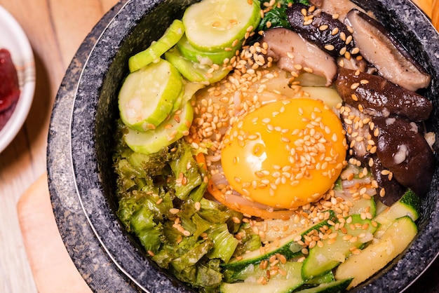 Bibimbap em uma tigela de pedra preta aquecida Prato tradicional coreano bibimbap arroz misto