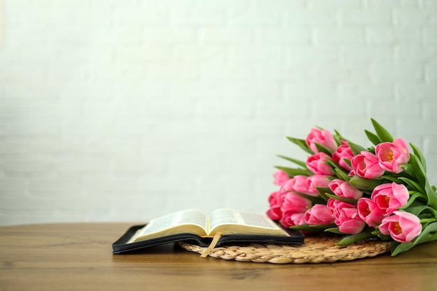 Biblia abierta con flores de tulipán en madera clara