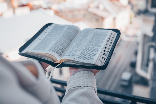 Biblia abierta en manos en el fondo de la ciudad