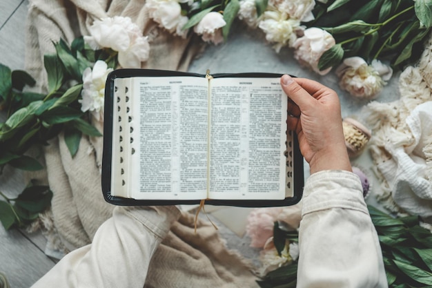 Biblia abierta en manos de una niña leyendo por la mañana