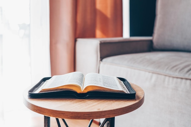 Biblia abierta en la mesa en el interior moderno de la sala de estar