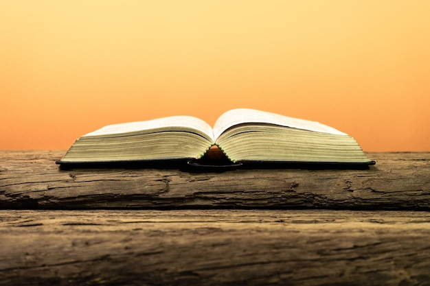 Biblia abierta y vela en una vieja mesa de madera de roble hermoso fondo naranja concepto religioso