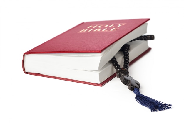 Biblia en un blanco. Libro sagrado y rosario de madera.