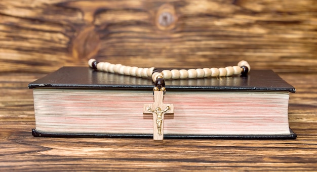 Bíblia com rosário em fundo de madeira