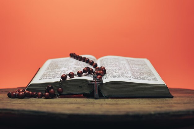 Biblia y el crucifijo cuentas en una vieja mesa redonda hermoso fondo de coral naranja religión oculta