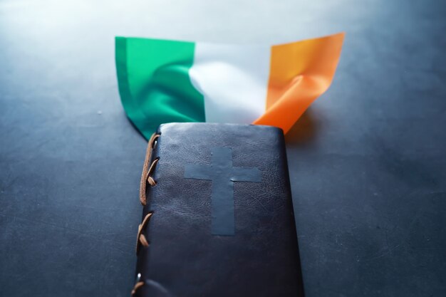 Una Biblia encuadernada en cuero sobre la mesa. Celebración religiosa cristiana irlandesa. Símbolo de trébol de cuatro hojas de buena suerte.