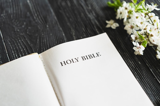 La biblia con flores de primavera en un concepto de fondo de madera para la fe