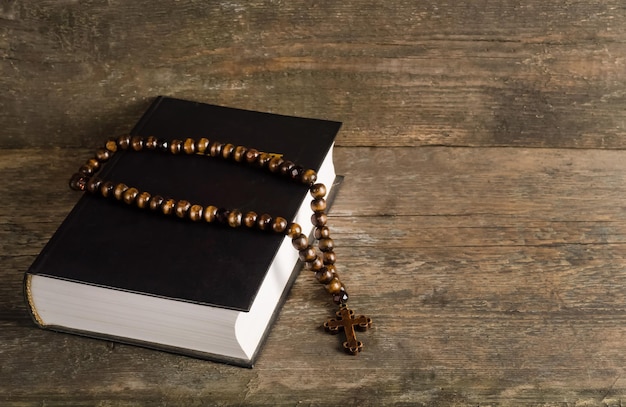 Biblia con rosario sobre fondo de madera vieja con espacio de copia, concepto de religión
