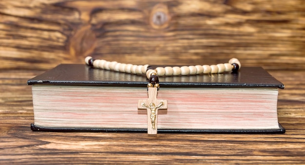 Biblia con rosario sobre fondo de madera