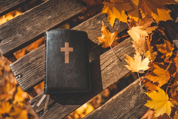 Biblia sobre un fondo de madera en hojas de otoño