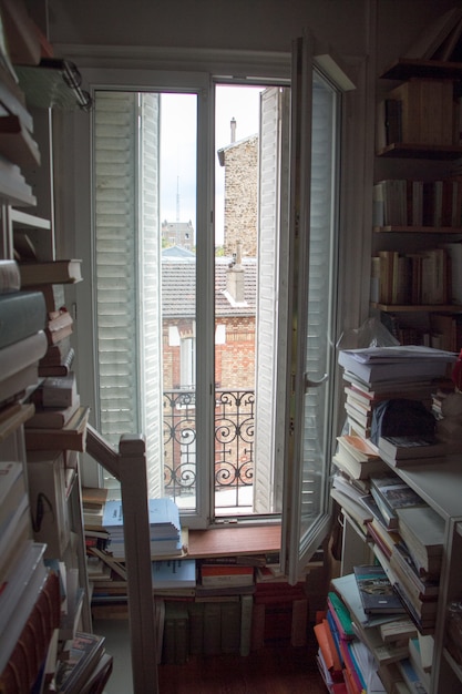 Foto biblioteca de casa con una gran cantidad de libros y una ventana con persianas en un pequeño apartamento