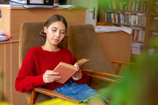 Biblioteca da universidade bela garota caucasiana sentada na cadeira ao lado da estante
