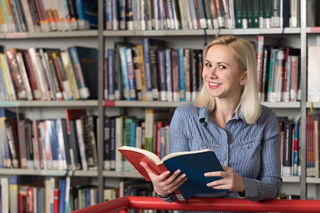 En la biblioteca Estudiante bastante femenina con libros Trabajando en una biblioteca universitaria de secundaria Profundidad de campo reducida
