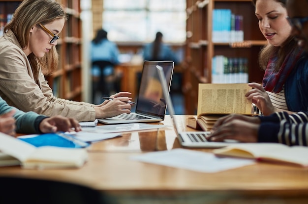 La biblioteca siempre está repleta durante la época de exámenes Foto de un grupo de estudiantes universitarios trabajando en la biblioteca del campus