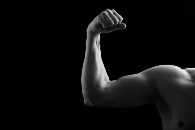 Bíceps musculares em um fundo preto Foto de estúdio do bíceps humano Corpo masculino sexy Mão humana