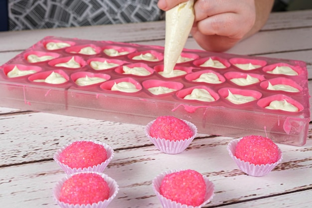 Bicho de pe, brasilianische Süßigkeit. Im Hintergrund ein Bäcker, der Bonbons mit Ganache füllt.