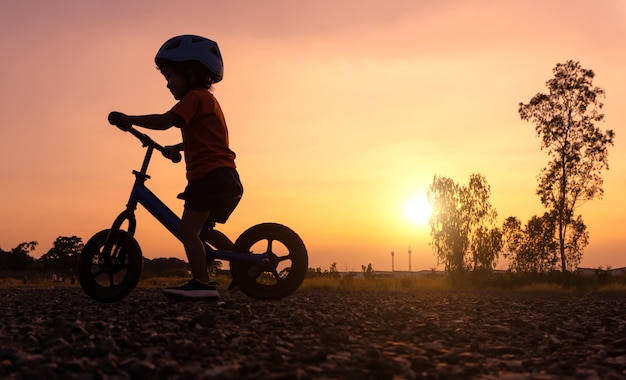 Bici del balanceo del primer día del juego del niño asiático de la silueta.