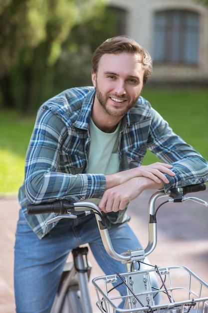 En una bici. Un hombre sonriente con una camisa a cuadros en una bicicleta