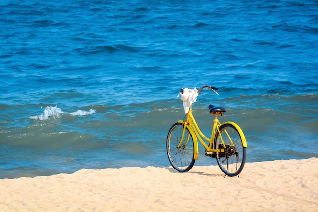 Bicicleta amarela na costa do mar azul.