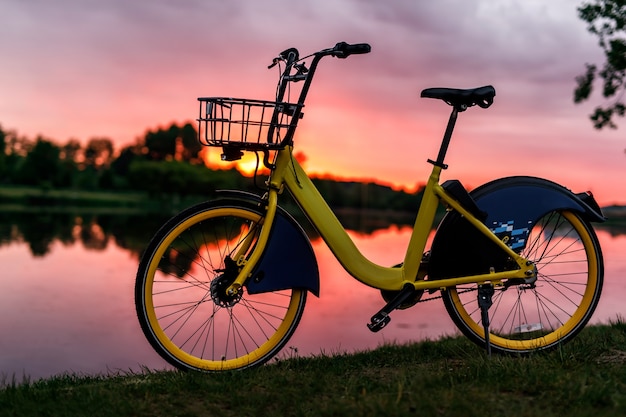 Bicicleta amarela no lago. Céu rosa pôr do sol