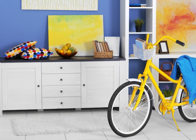 Foto bicicleta amarilla con cubierta azul en el interior de la sala de estar ligera