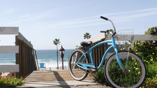 Bicicleta azul, bicicleta de crucero, costa de la playa del océano, orilla del mar de California, EE. UU. Palmeras tropicales y salvavidas