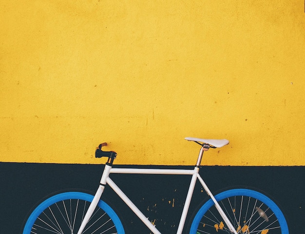 Bicicleta azul contra a parede amarela