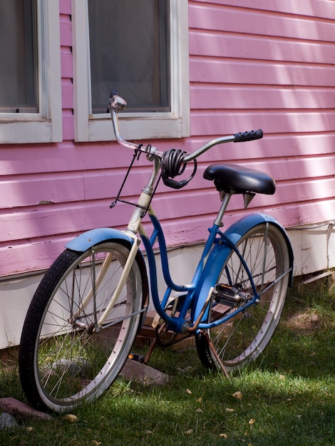 Bicicleta azul estacionada al costado de la casa rosada. Fila de casas de muñecas históricas en Telluride, Colorado. Cada casa está pintada con colores vivos.