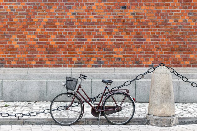 Bicicleta com cesto perto da parede de tijolo vermelho. conceito de estilo de vida urbano e ecológico para transporte na cidade velha