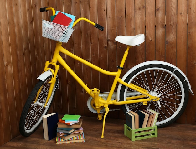 Bicicleta com livros na caixa no fundo da parede de madeira