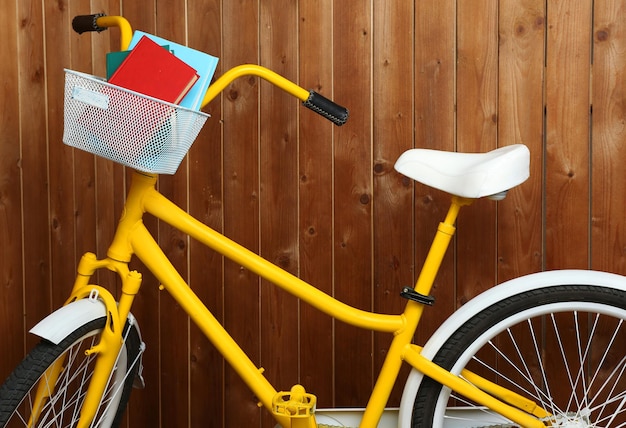 Bicicleta com livros sobre fundo de parede de madeira