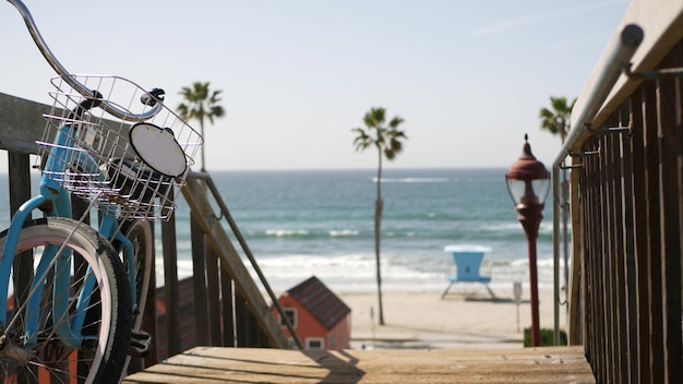 Bicicleta de crucero por Ocean Beach, costa de California, Estados Unidos. Ciclo de verano, escaleras y palmeras.