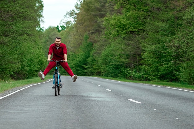 Bicicleta de equitação masculino feliz com as pernas para cima. A estrada na floresta. O conceito de um estilo de vida saudável, cardio-training. Copyspace.