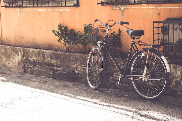 bicicleta de época estacionada en la antigua muralla en la calle estrecha urbana (estilos de tono de color vintage)