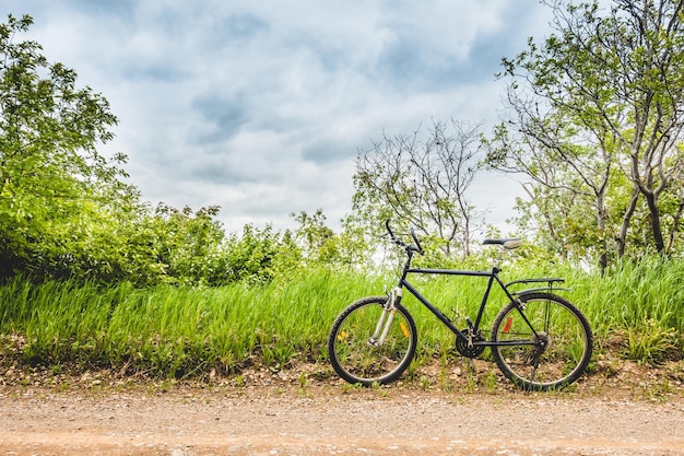 Bicicleta estacionada ao lado de uma estrada de cascalho com campo ao fundo