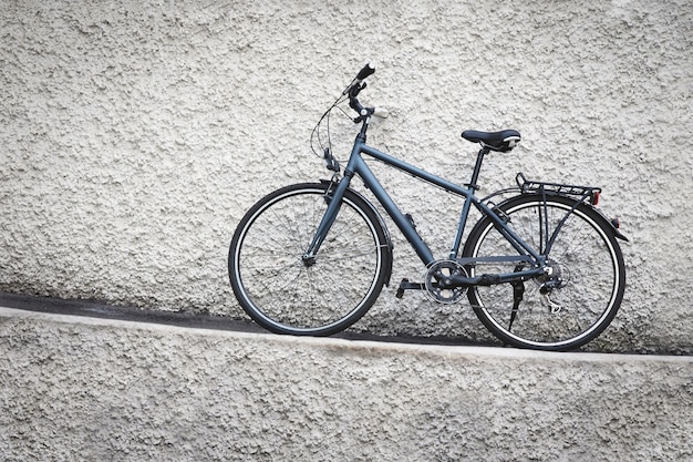 Bicicleta estacionada contra parede de pedra suja