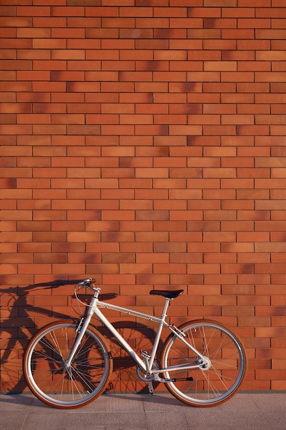 Bicicleta estacionada perto de parede de tijolos