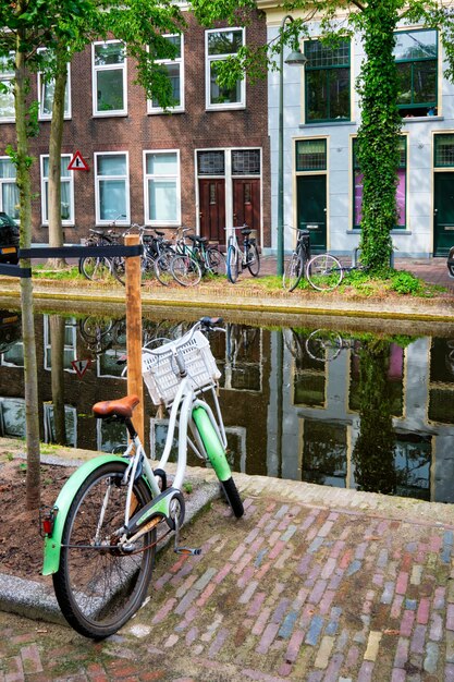 Bicicleta estacionada perto do canal na rua delft com casas antigas delft holanda