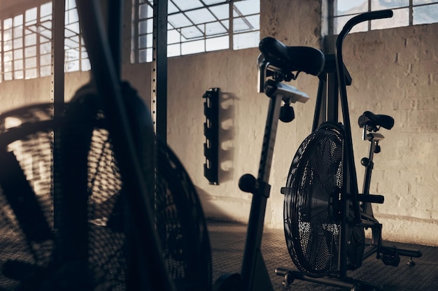 Foto bicicleta giratoria vacía y gimnasio para hacer ejercicio con un fondo de sombra en un almacén con luz bicicleta de cardio club para equipos de fitness para entrenamiento y entrenamiento en un lugar de almacenamiento en la oscuridad