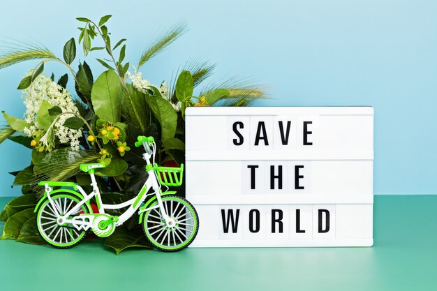 Bicicleta de juguete y caja de luz con texto salvan el mundo. Día sin coches, día mundial de la bicicleta, protección del medio ambiente, concepto de estilo de vida sostenible con espacio de copia